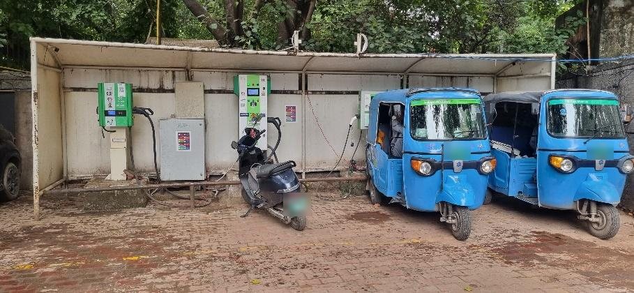 An EVIT station in a Delhi municipal parking lot, charging e-rickshaws and a scooter
